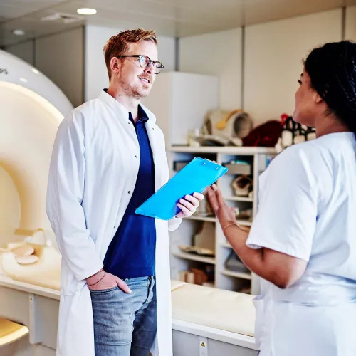 Medizinisches Fachpersonal im Gespräch vor einem MRT-Gerät.