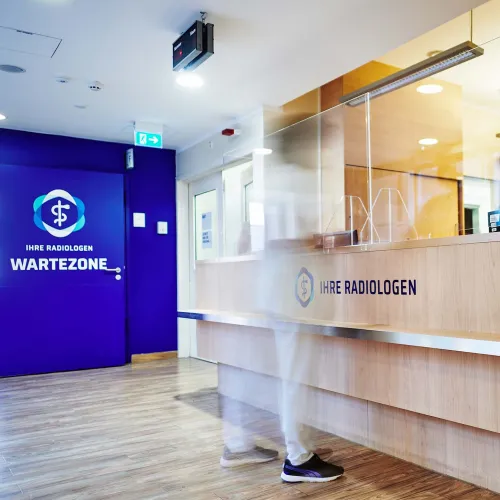 Empfangsbereich mit Holztheke und blauer Wand im Wartebereich.